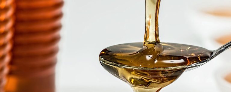 Sirup auf einem Löffel, vor einem unscharfen Hintergrund, der eine Ernährung für Fitnesskunden symbolisiert.