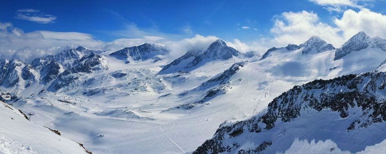 Schneebedeckte Berggipfel und Skipisten, ideal für aktiven Wintersport und Fitness.