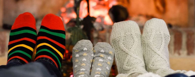 Gemütliche Füße in Stricksocken am Kaminfeuer, perfekt für die Erholung nach dem Training.