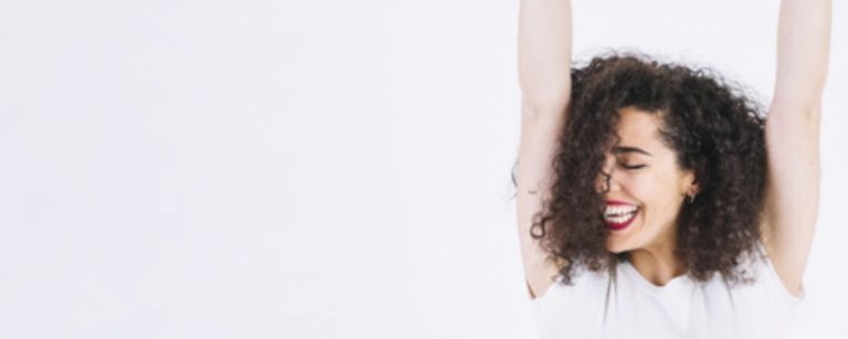 Frau mit Locken und roten Lippen, die lacht, vor weißem Hintergrund für Fitness-Ernährung.