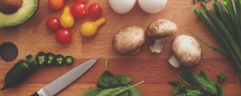 Schnittlauch, Pilze, Tomaten, Avocado, Jalapenos und Eier auf einem Holzbrett – Zutaten für gesunde Fitness-Mahlzeiten.