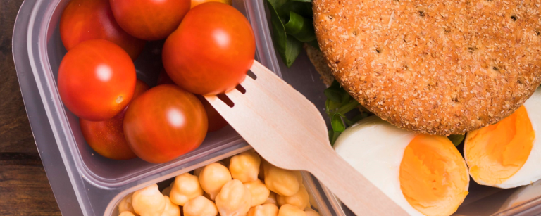 Gesunde Mahlzeit: Tomaten, Kichererbsen, Ei und Vollkornbrot im Bento-Behälter.