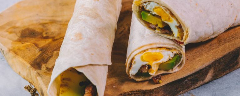 Frühstücks-Burrito mit Ei, Avocado und Speck für einen energiegeladenen Start.