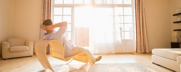 Mann entspannt in einem modernen Wohnzimmer, umgeben von hellem Licht.