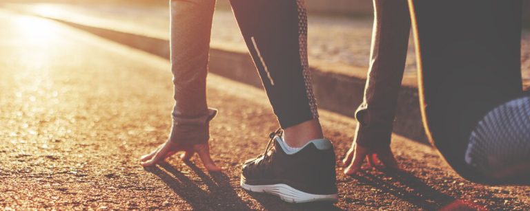 Läuferin in Startposition im Sonnenuntergang für Fitness und Ernährung.